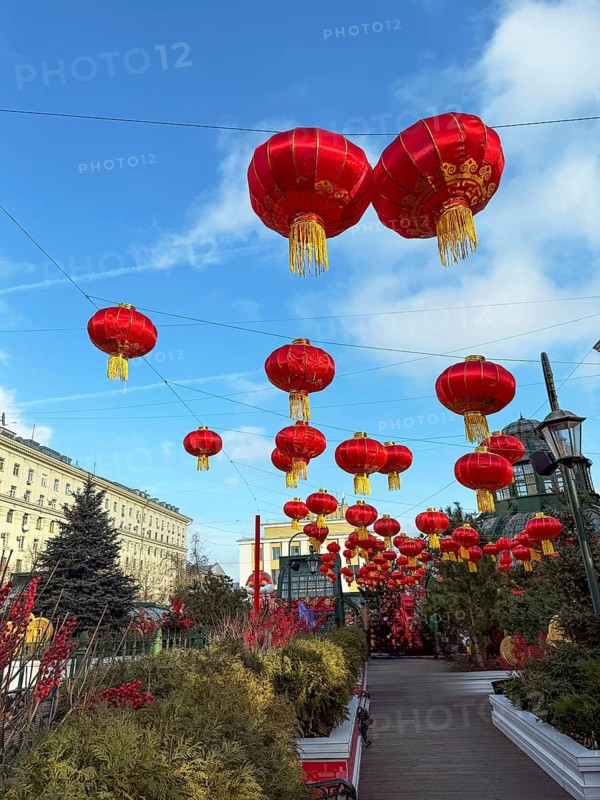 Street adorned with vibrant red Chinese New Year lanterns hanging under a clear blue sky, celebrating the festive atmosphere and cultural traditions in an urban setting