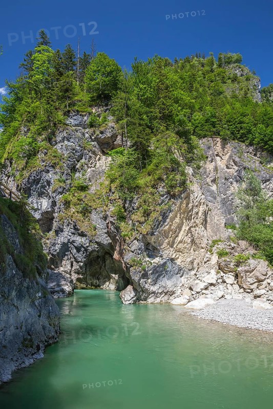 The Lammer creek is flowing fast through the Lammerklamm on a sunny hiking day. Blue sky, turquoise water and green trees