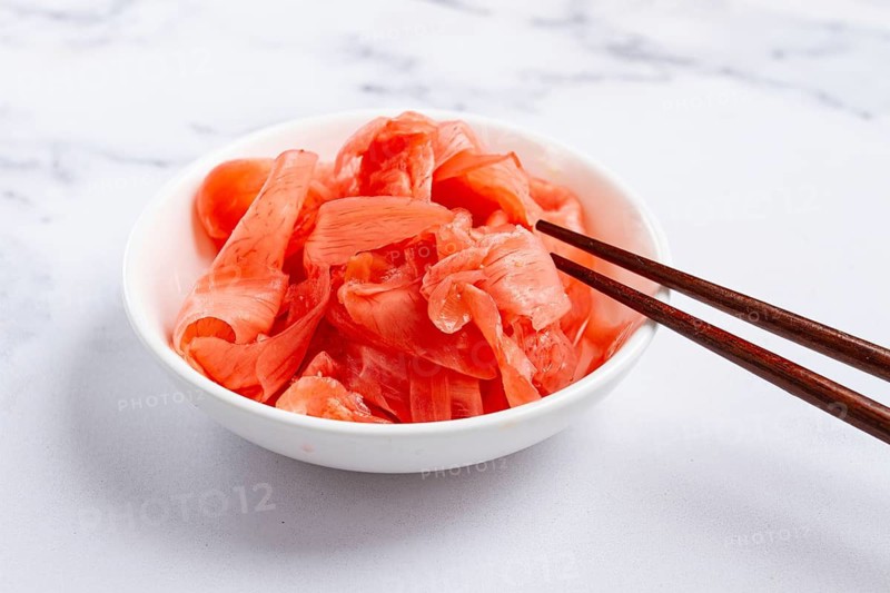 Pickled ginger, with chopsticks, in a small white bowl, on a marble countertop, close-up, no people