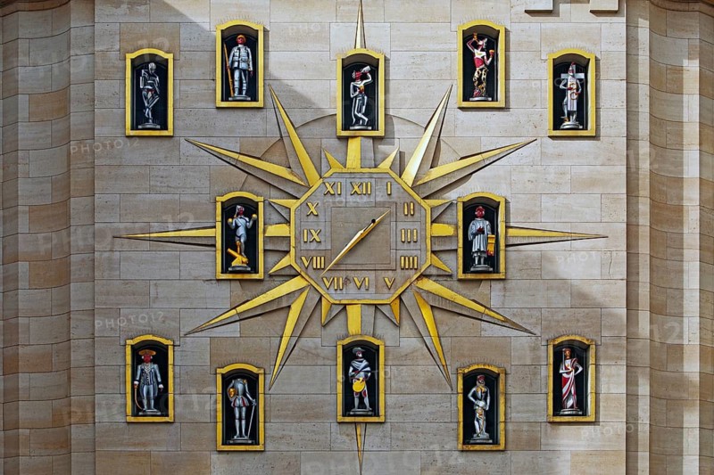 Large golden wall clock with twelve figures at the back of the Dynasty Palace, Brussels, Belgium
