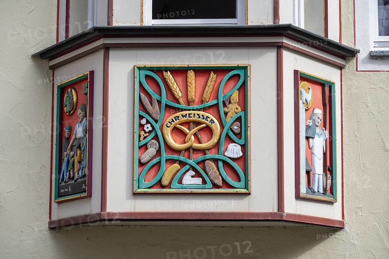 Detailed view of a town house, in the historic old town of Rottweil with an artfully decorated bay window, The central coat of arms on the photo shows a pretzel with the inscription Chr. Weisser, above it wheat ears and craft scenes which indicate the historic use of the building as a bakery, Rottweil district, Baden-Württemberg, Germany