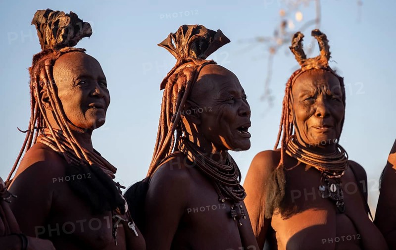 Three old married Himba woman with traditional hair jewellery singing, portraits, near Opuwo, Kaokoveld, Kunene, Namibia