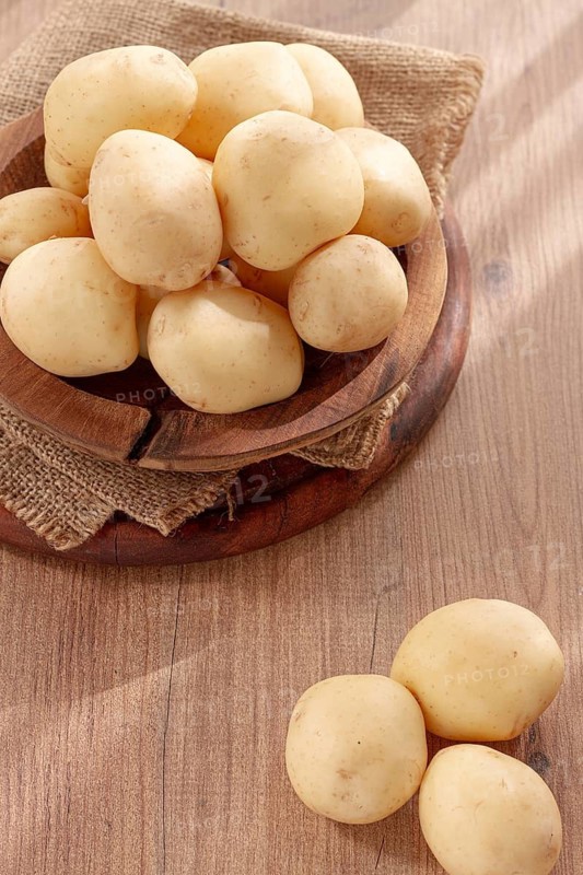 Boiled new potatoes, in a wooden bowl, on a rustic table, natural light, no people