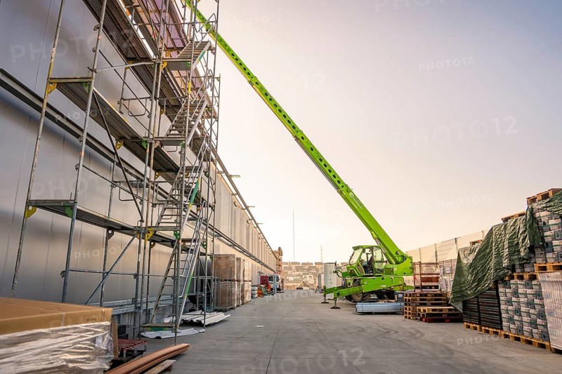 Construction site with tall crane and scaffolding, building materials are spread over a wide road, PV assembly at OBI Baumarkt, Mühlacker, Enzkreis, Germany