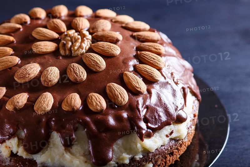 Homemade chocolate cake with milk cream and almonds on black wooden background. close up