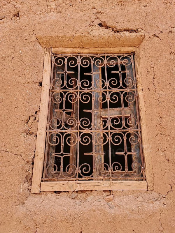 An old window with grid in a clay wall gives a rustic impression, Morocco