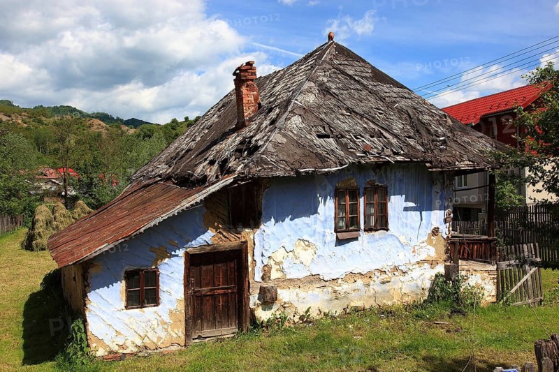 Traditional Romanian farmhouse that is in a dilapidated or abandoned state. The eye-catching light blue color of the outer walls is common in many Romanian villages, such houses are characteristic of rural regions in Romania, particularly Transylvania, Transylvania