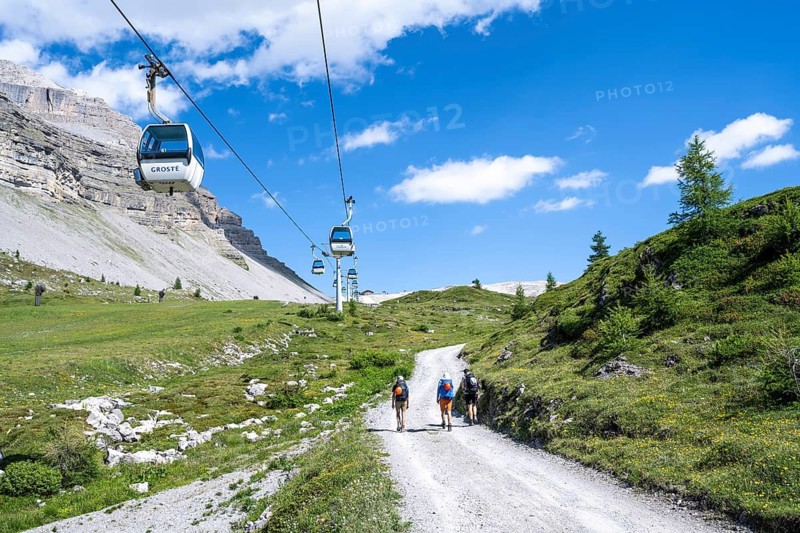 Hikers on a road, climbing to Rifugio Graffer below the Grosté cable car, Brenta, Brenta-Adamello Natural Park, Trentino, Italy