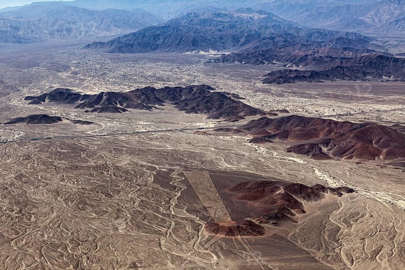 View from the air of a desert landscape with mountains and unusual line patterns, the geoglyphs and drawings in the desert near Nasca and Palpa in Peru