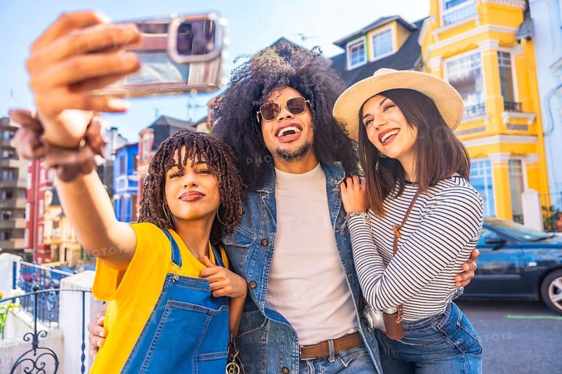 Three happy tourists taking a selfie with colorful buildings in the background, enjoying their vacation and exploring a vibrant city