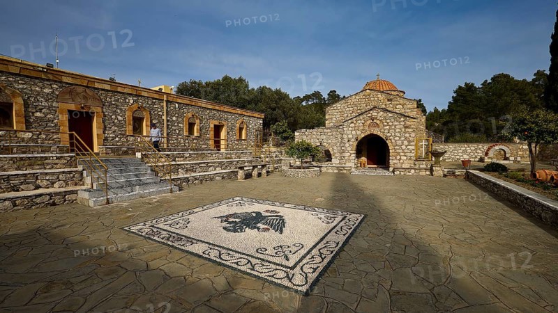 Stone building with church and mosaic in the courtyard under a blue sky, surrounded by trees, Thari Monastery, Moni Thari, near Gadouras Reservoir, lonely mountain region, Rhodes, Dodecanese, Greek Islands, Greece