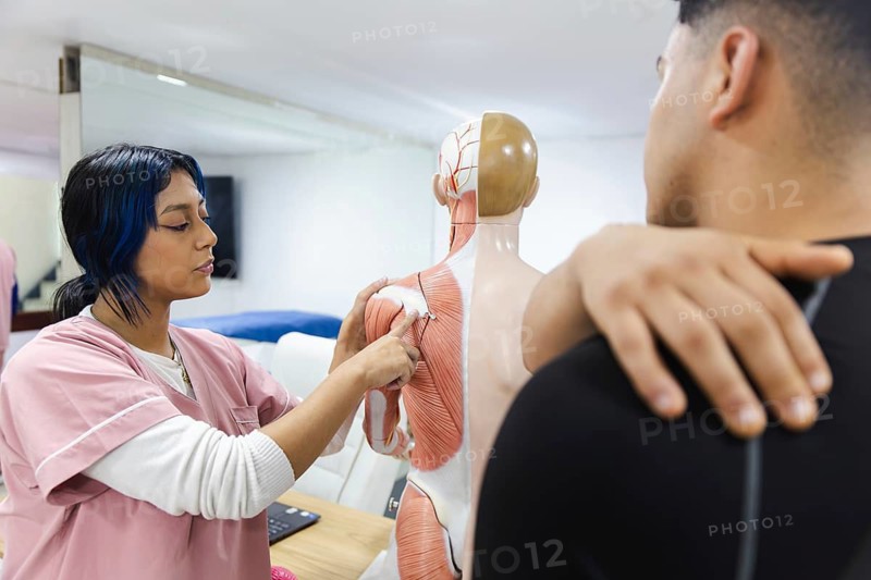 A physiotherapist educates a patient using an anatomical model in an Ecuador clinic, demonstrating effective therapy techniques in a professional setting
