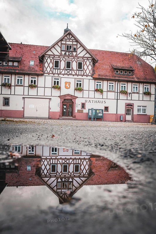 Historic town hall with reflection in puddle, Hirsau, Calw, Black Forest, Germany