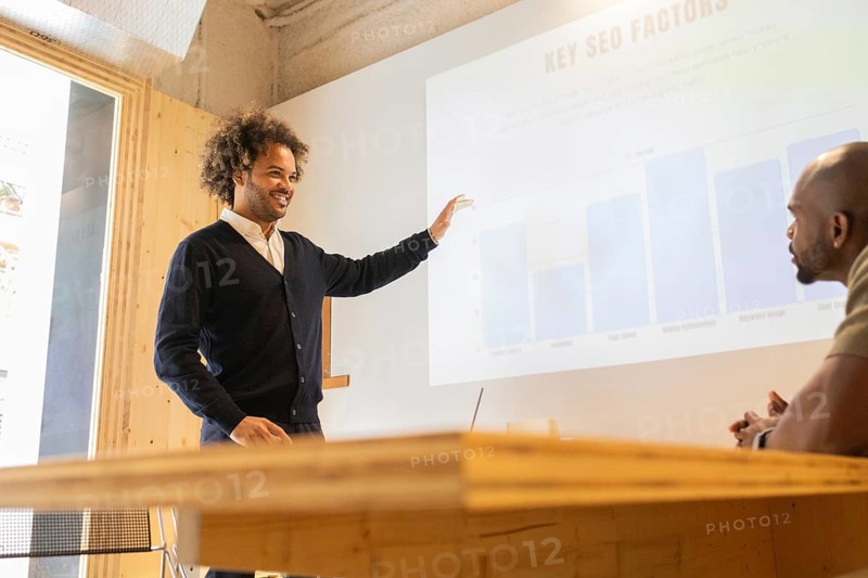 A professional giving a presentation in a modern coworking space in Barcelona. The setting features a wooden table and comfortable chairs, fostering an inspiring work environment