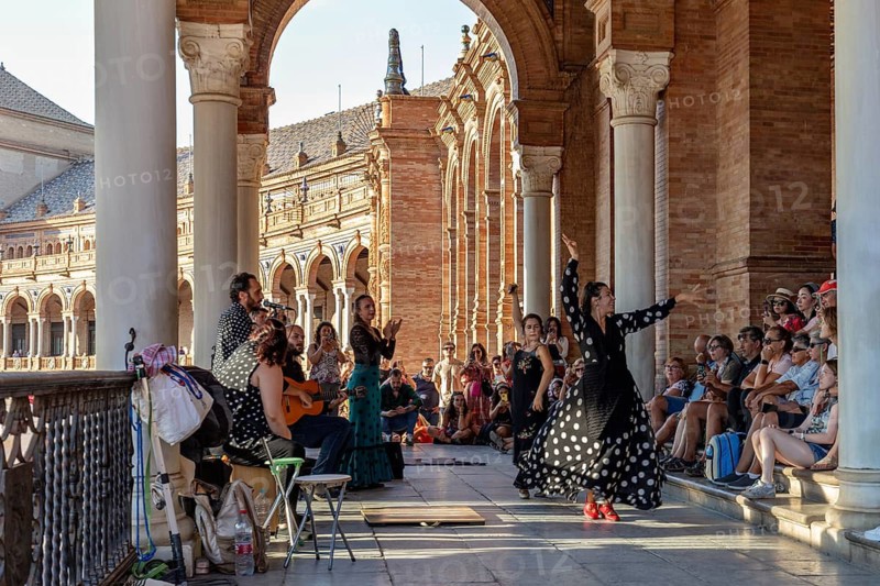 Flamenco dancers and musicians impress the audience against a backdrop of historic architecture, Seville