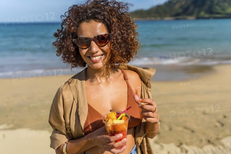 Arab female modern traveler eating tropical fruit on a sandy beach