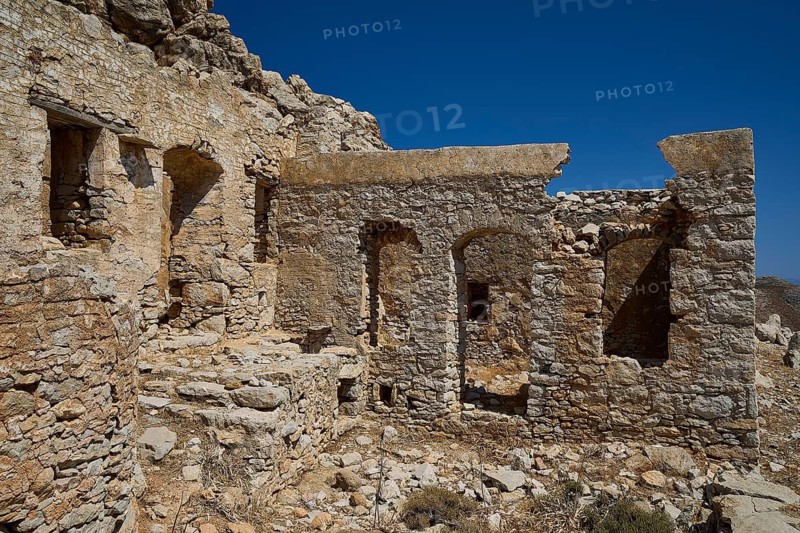 Weathered ancient stone ruins with blue sky in the background, historic atmosphere, lost place, abandoned village, micro chorio, church of the Assumption of Mary, zero waste island, Tilos, Dodecanese, Greek islands, Greece