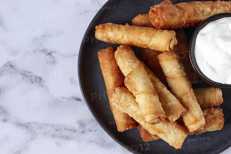 Fried spring rolls with cheese, on a plate, with cream sauce, no people