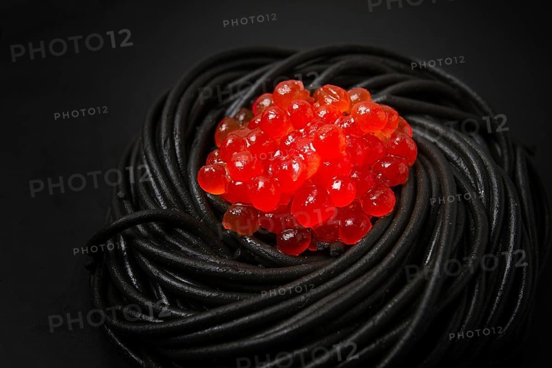 Black spaghetti with red caviar, pasta, on a black background, top view, no people