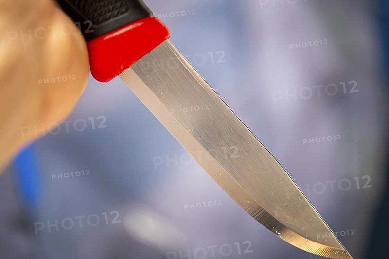 Symbolic image of a knife attack: close-up of a knife in a man's hand