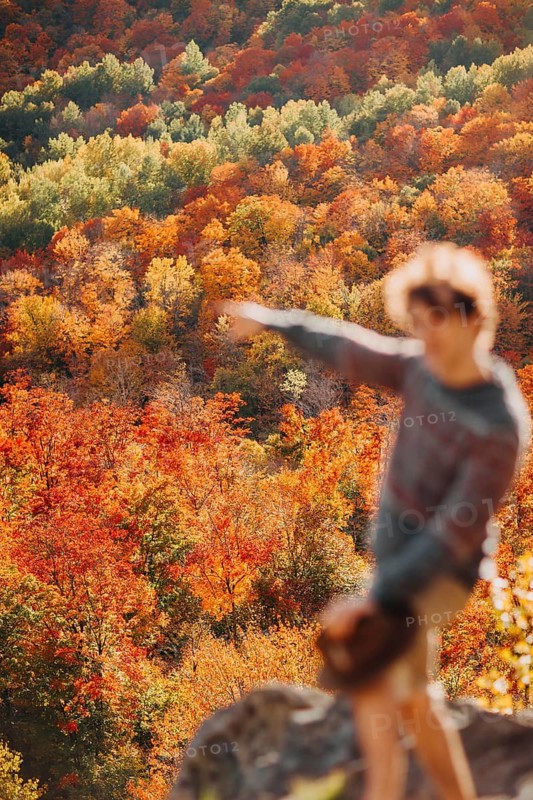 A man stands amidst the vibrant autumn foliage in Quebec, Canada, enjoying the stunning array of red, orange, and yellow leaves. The fall season is in full display
