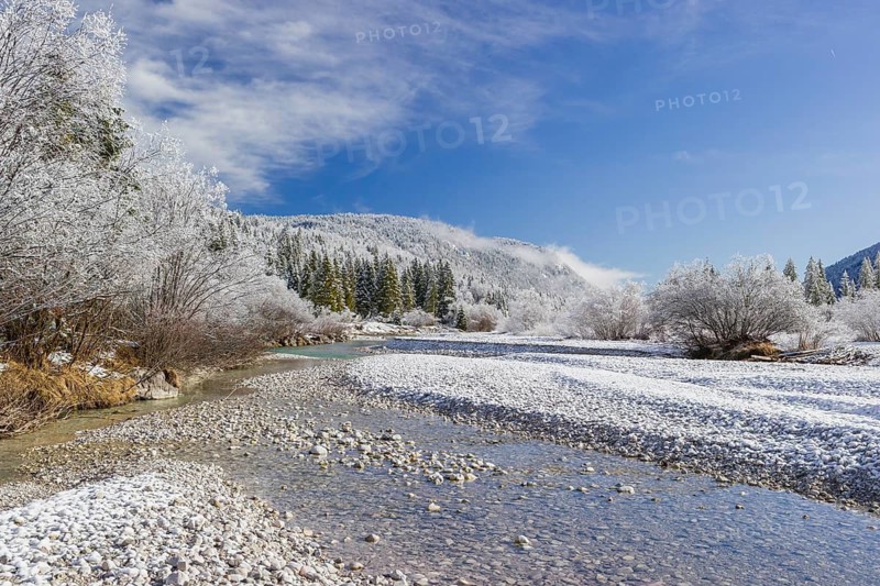 Isar valley in winter at temperatures of minus 18 degrees Celsius. Snow covered landscape with the Isar river flowing through. Some hoar frosted trees. Early morning