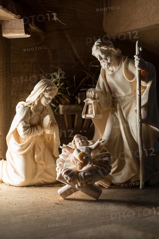 The Holy Family at the crib, wooden crib figurines represent the birth of Jesus Christ Child lying in a crib in a stable as a little Christ Child, Christmas
