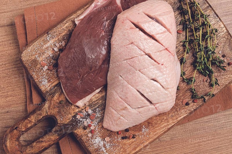 Fresh raw duck breasts, on a wooden chopping board, with herbs and spices, no people
