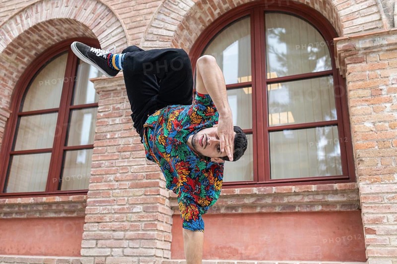 A dynamic Cuban dancer performing a vibrant pose against an urban backdrop. The colorful attire and expressive movement capture the essence of Cuban dance and culture