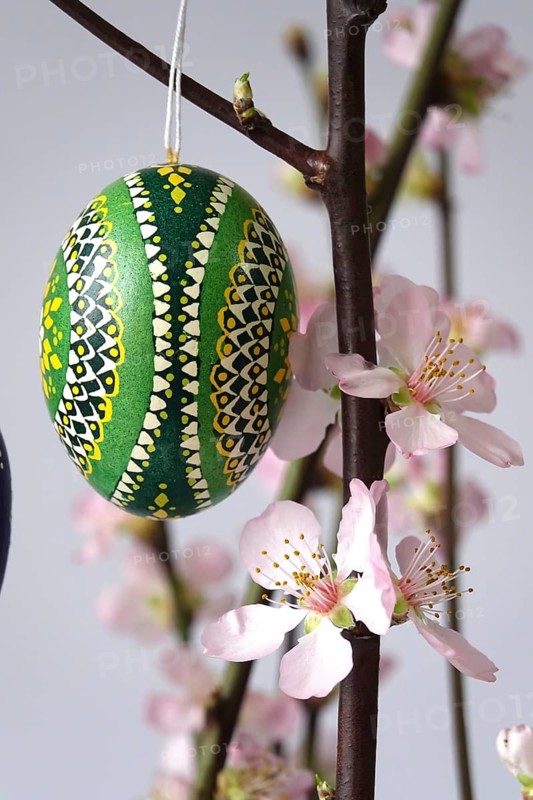 Blooming branches of a peach tree in a vase decorated with Easter eggs, spring, Germany
