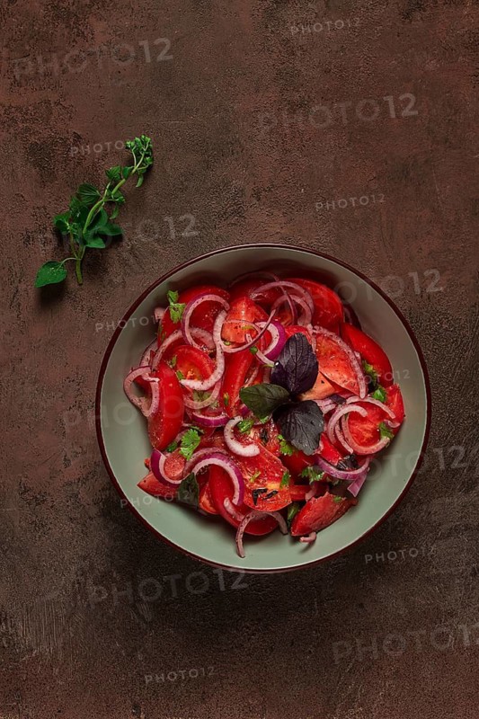 Fresh tomato salad, with red onion, spices and herbs, top view, close-up, homemade