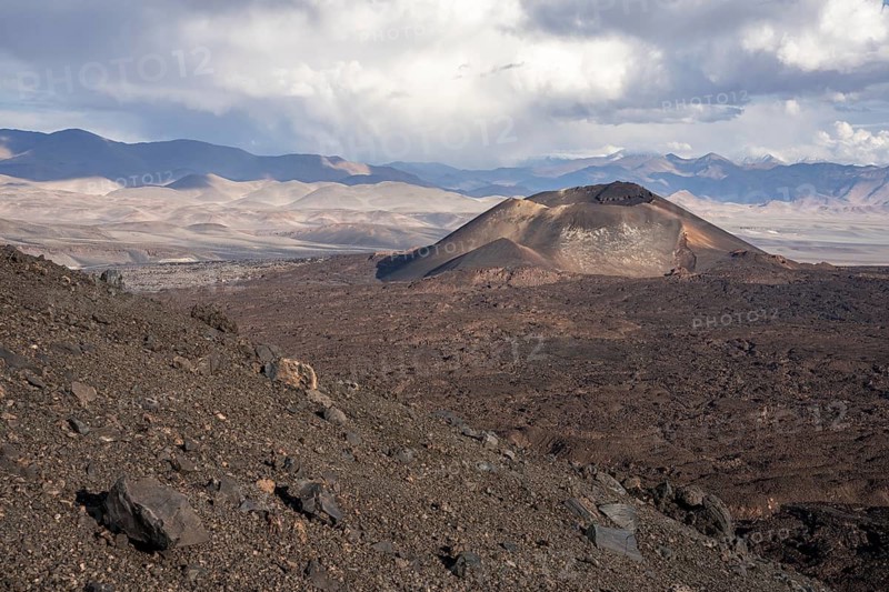 A slope with volcano and rocky terrain, surrounded by a mountain range, Argentina, volcanoes, lava field, Antofagasta