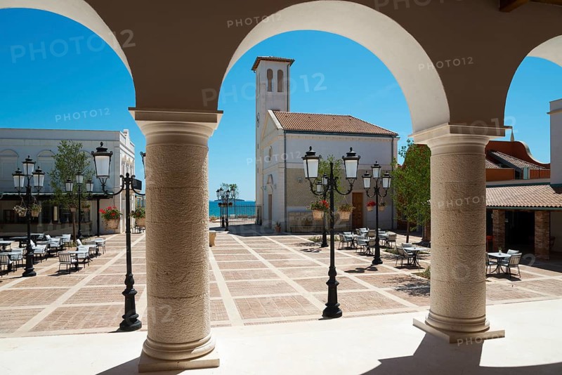 View through arches to a sunlit square with a church in the background, Amadria Park, Sibenik, Šibenik-Knin, Dalmatia, Croatia