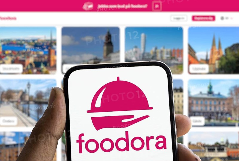 Foodora logo is displayed on smartphone. Foodora is an online food delivery brand owned by Delivery Hero