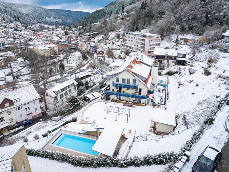Bird's eye view of a snow-covered town with colourful houses and forests in the background, Bad Wildbad, Black Forest, Germany