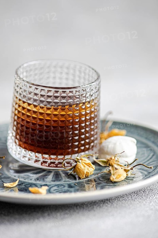 A delicate vanilla mini zephyr-marshmallow filled with rose jam, served alongside a refreshing coffee liqueur drink with ice, creating a delightful pairing