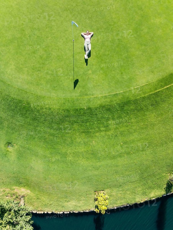 Woman lying on the green at the La Noria Golf Resort. Aerial view. Drone shot. Málaga province, Andalusia, Spain