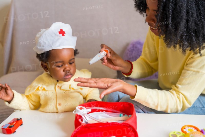 African mother and daughter playing doctors dressed like nurses at home