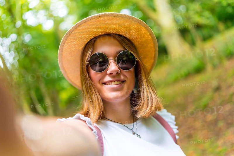Personal point of view of a caucasian happy young woman taking a selfie while hiking in the forest