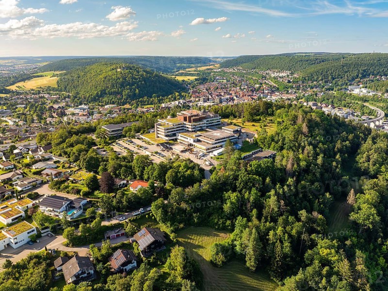Aerial view of a town in green surroundings, many houses and a large building on a hill, blue sky in summer, hospital, Nagold, Black Forest, Germany