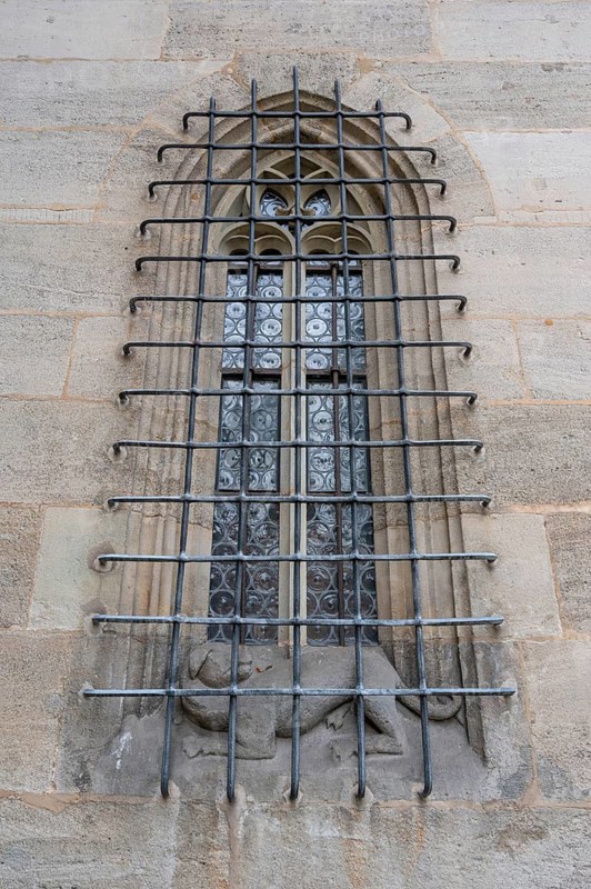 Pointed arch window with iron grating with a dog sculpture, late Gothic hall church of St George, Dinklesbühl, Bavaria, Germany