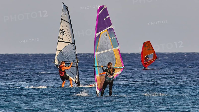 Three windsurfers navigating over the blue sea under clear skies, windsurfing, Meltemi windsurfing spot, Devils Bay, Paralia Vatha, Vatha Beach, south-east coast, Karpathos, Dodecanese, Greek Islands, Greece