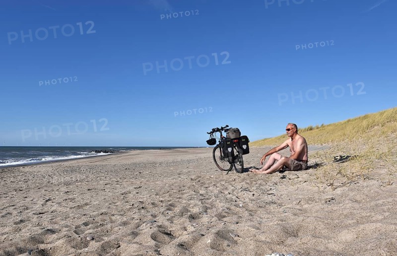 Senior takes a break by bike on the beach in Denmark