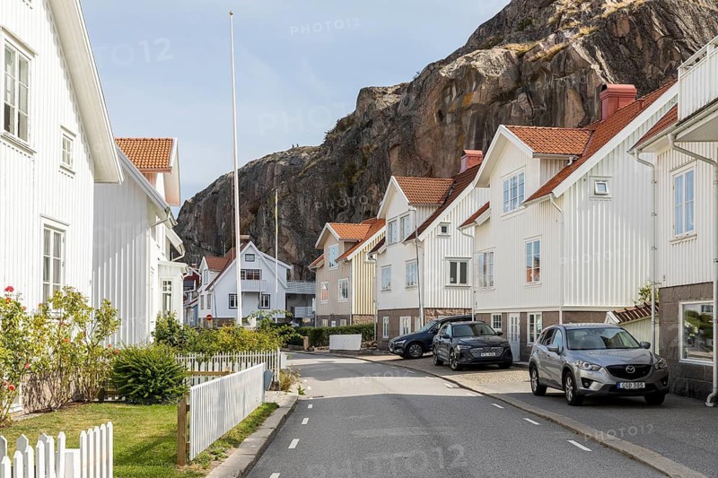 Typical wooden houses in front of the steep rock face of the Vetteberg in Fjällbacka, Västra Götalands län, Sweden