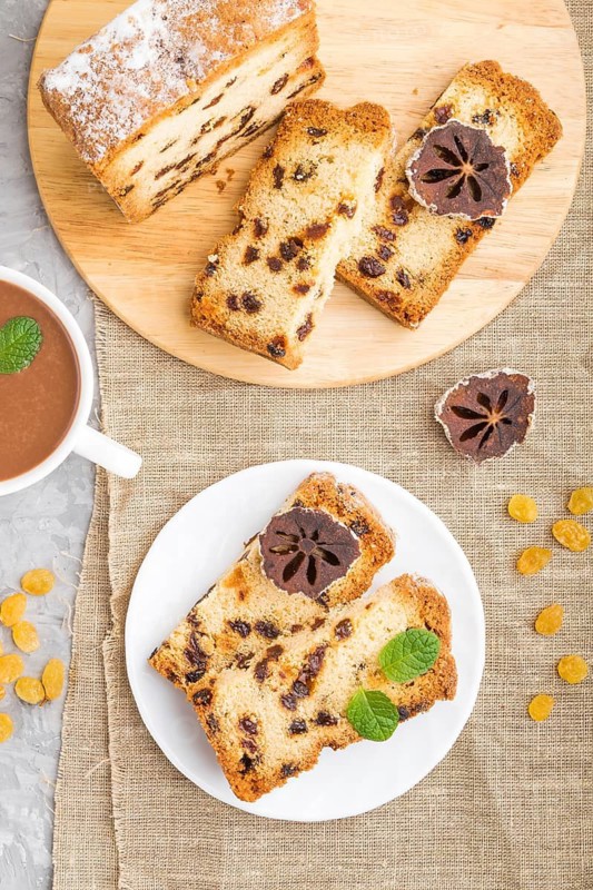 Homemade cake with raisins, dried persimmon and a cup of hot chocolate on a gray concrete background and linen textile. top view, flat lay, close up