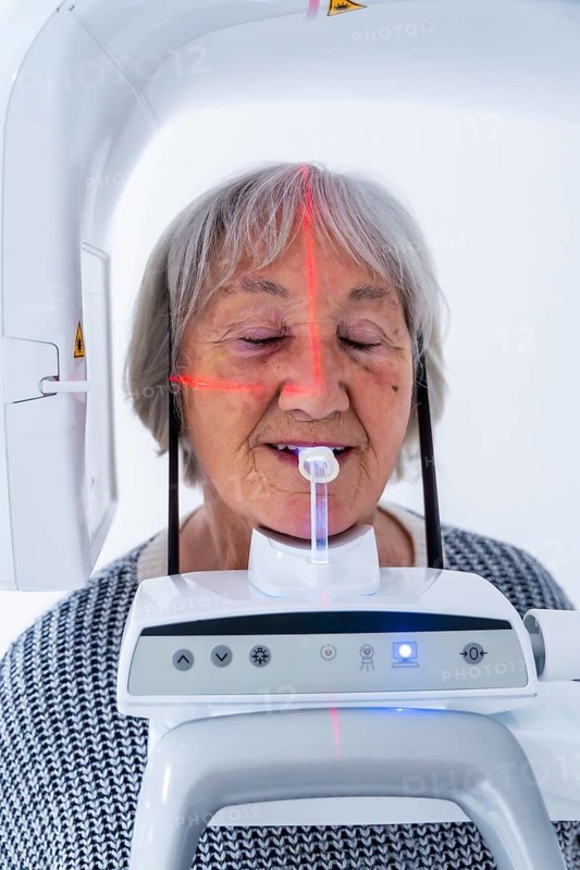 Senior woman undergoing a dental x ray scan with advanced equipment in a modern dental clinic, ensuring accurate diagnosis and treatment planning