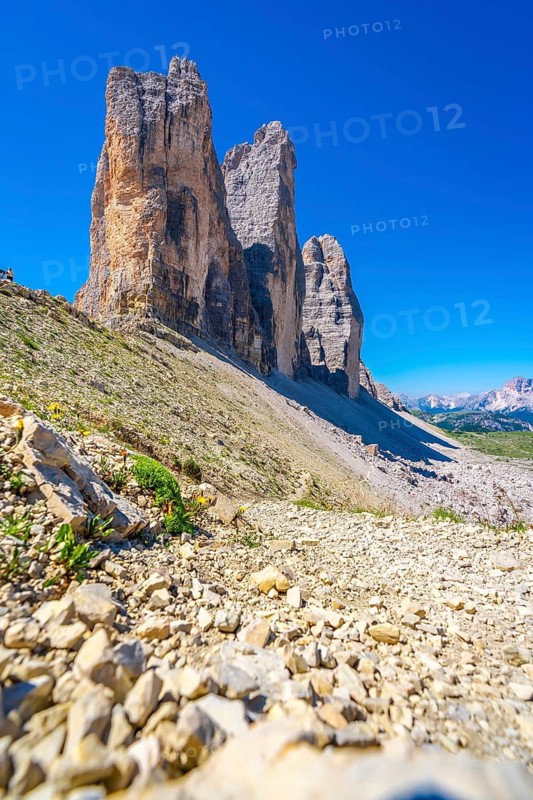 Rocky hiking trail leading to the majestic tre cime di lavaredo peaks in the dolomites, italy, on a sunny summer day