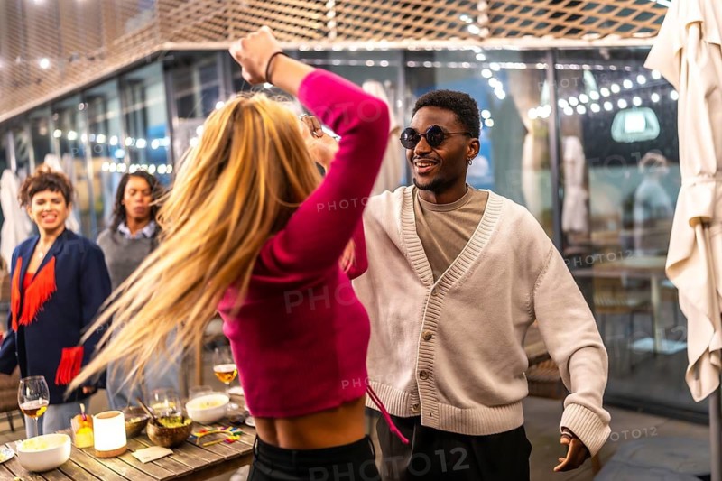 Three quarter length photo of multi-ethnic friends dancing together at outdoors terrace at night bar