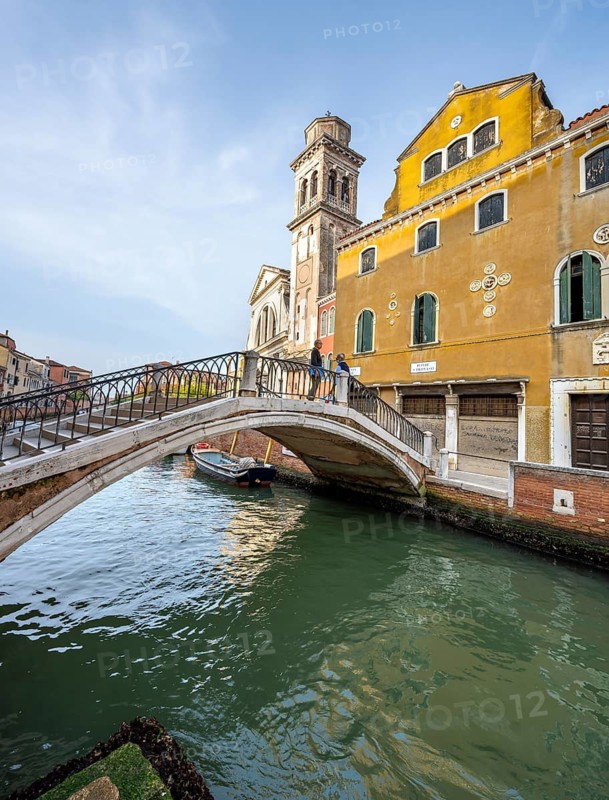 Bridge over a canal, yellow house facade and church, Venice, Veneto, Italy
