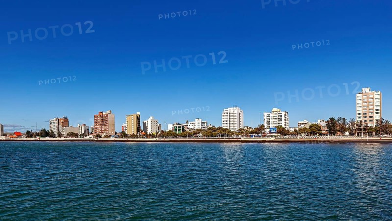 Skyline of a coastal town with tall buildings on a sunny day and calm water, the city of Puerto Madryn in Argentina